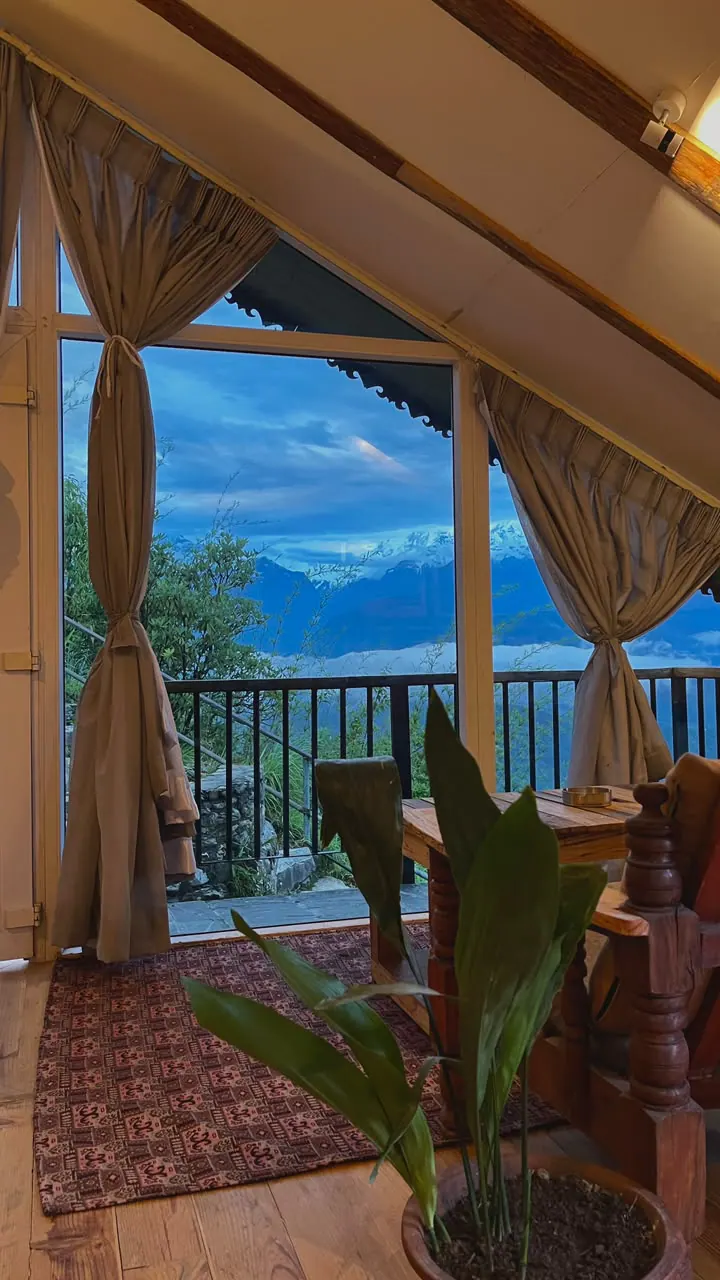 View from the Attic room through its glass gable and veranda railing to snow-capped peaks in the early morning